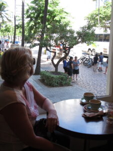 Jo Muirhead looking out the window of a cafe in Hawaii looking onto a garden from an open window 